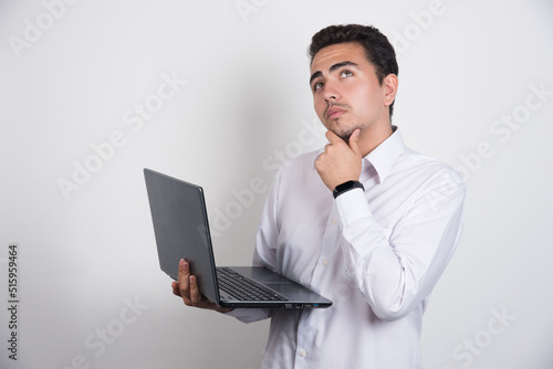 Businessman with laptop thinking on white background