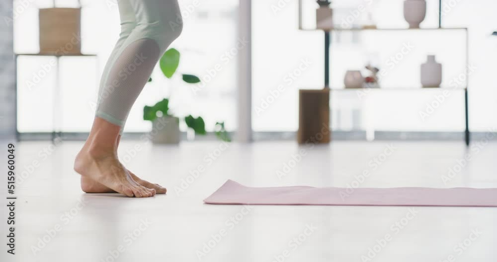 A woman rolls out a yoga mat on the floor in a yoga fitness training room. Active and fit barefoot woman prepares for a home workout to live a healthy lifestyle with a balanced mind and body at home A woman rolls out a yoga mat on the floor in a yoga fitness training room. Active and fit barefoot woman prepares for a home workout to live a healthy lifestyle with a balanced mind and body at home