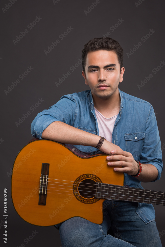 Obraz premium Serious man holding a guitar on dark background