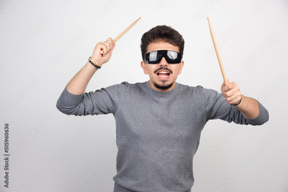 A drummer in black sunglasses holding drum sticks and looks very energic A drummer in black sunglasses holding drum sticks and looks very energic