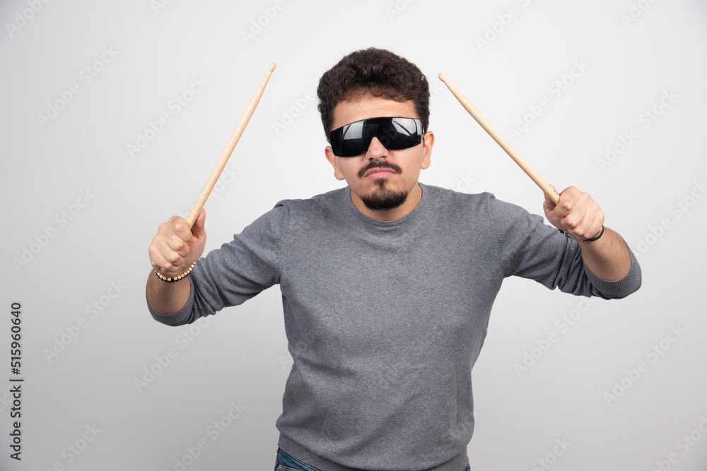 A drummer in black sunglasses holding drum sticks and looks very energic A drummer in black sunglasses holding drum sticks and looks very energic
