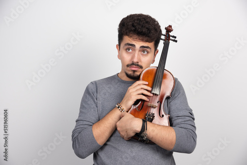 A musician holding his brown wooden violin and looks stressed