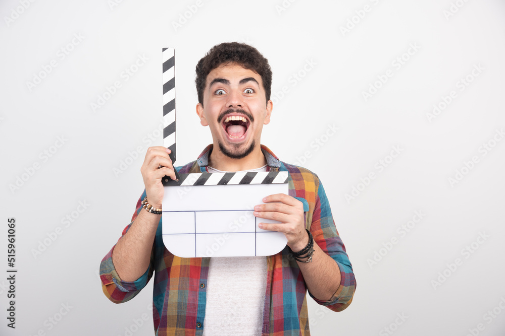 A filmmaker holding blank clapper board, opening it and laughing loud through it A filmmaker holding blank clapper board, opening it and laughing loud through it