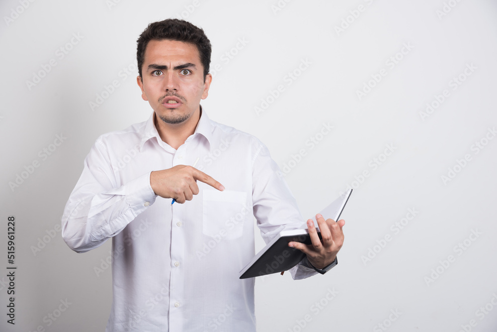 Angry businessman pointing at notebook on white background Angry businessman pointing at notebook on white background
