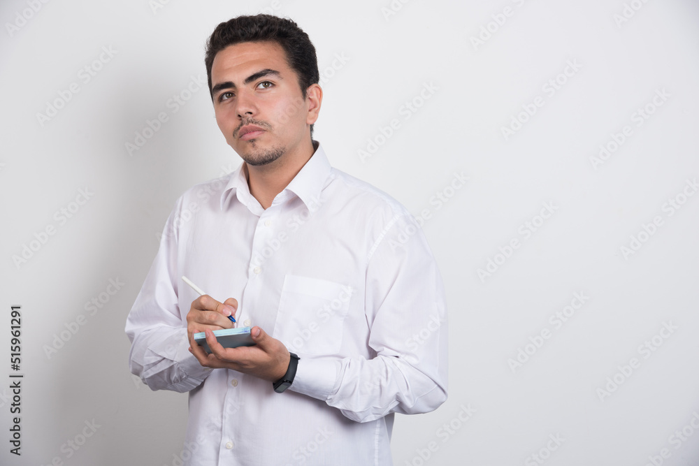 Young businessman writing on white background