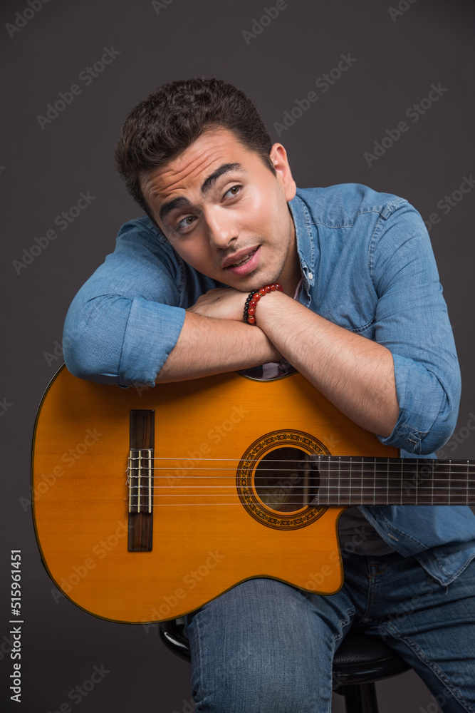 Obraz premium Brunette man with guitar looking his side on dark background