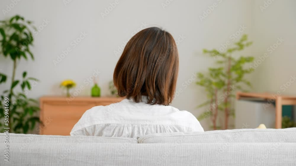 ソファーに座りながら横に揺れている若い女性 ソファーに座りながら横に揺れている若い女性