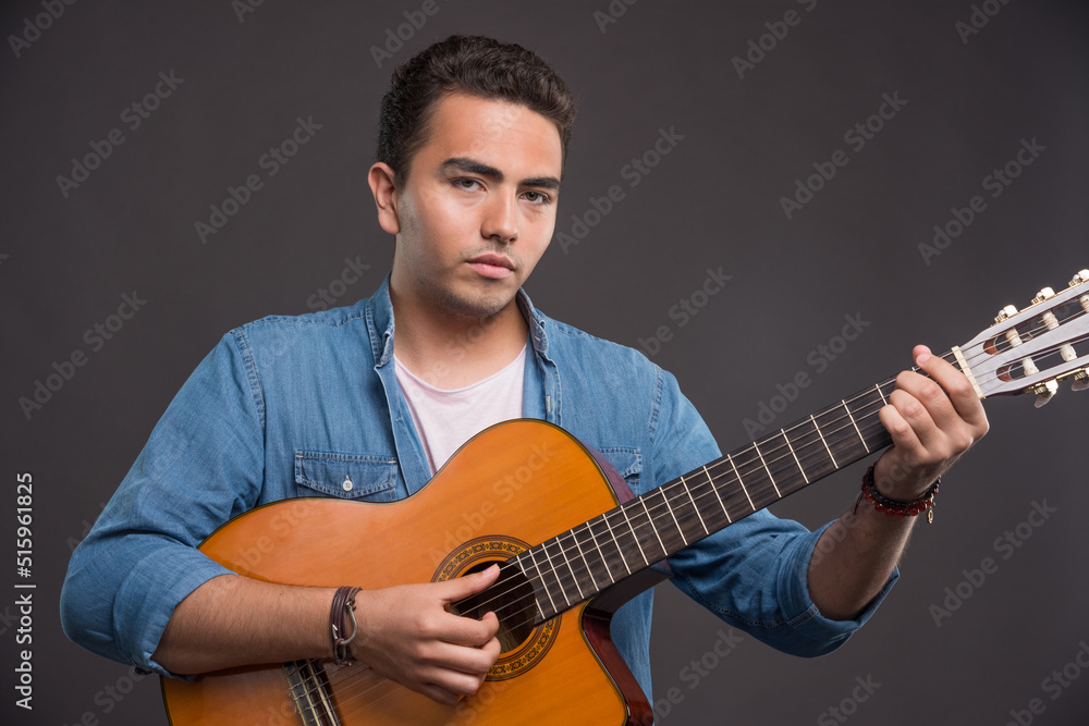Obraz premium Young man playing guitar on dark background
