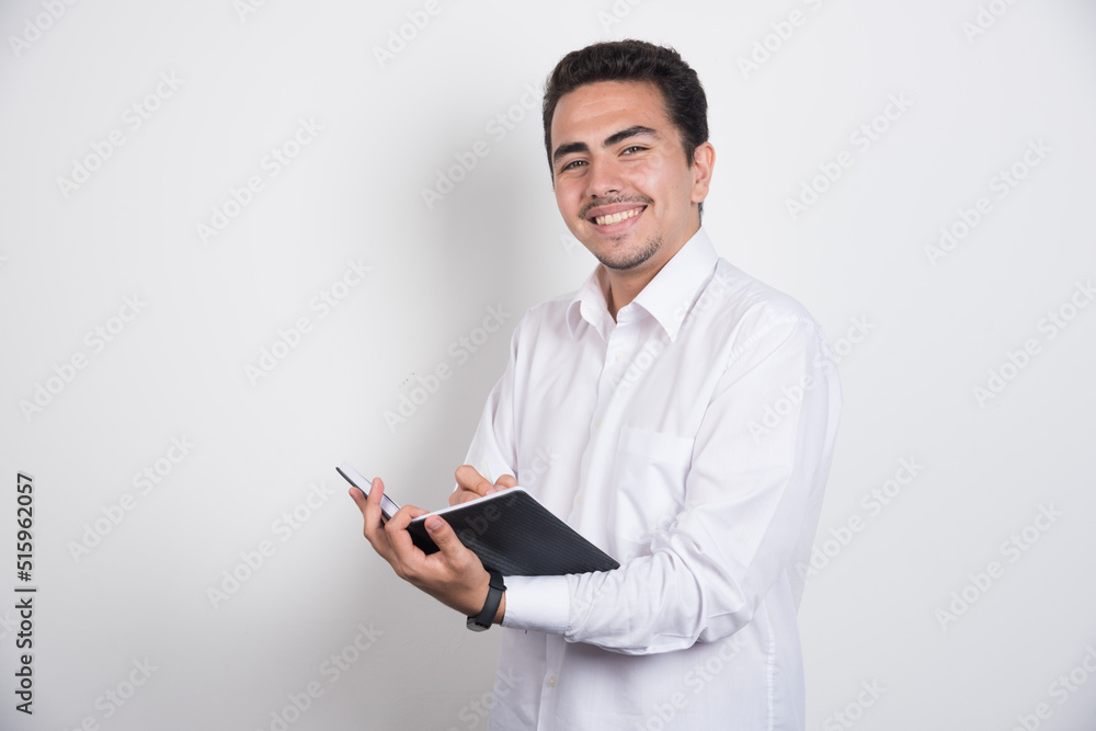 Smiling businessman with notebook posing on white background