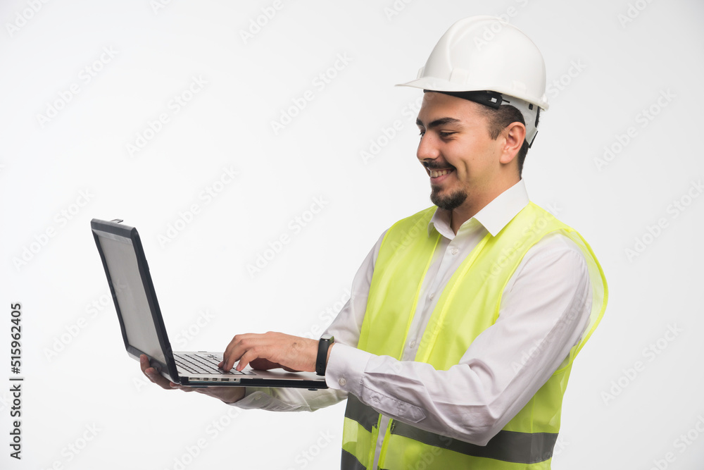 Engineer in uniform holding a laptop and writing Engineer in uniform holding a laptop and writing