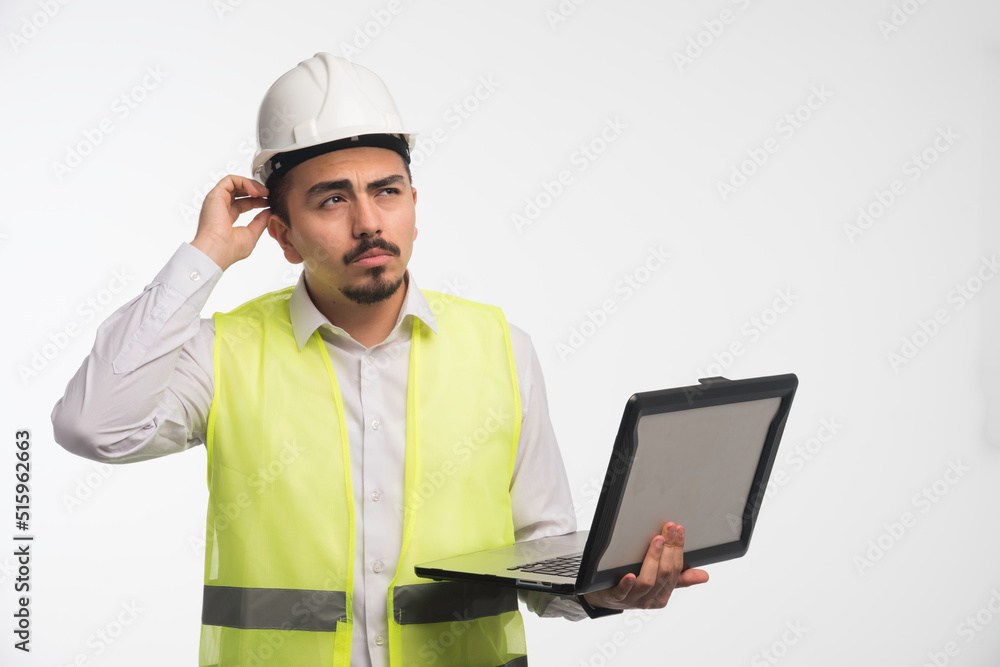 Engineer in uniform holding a laptop and thinking Engineer in uniform holding a laptop and thinking