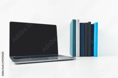 Laptop mock up with blank or empty screen with book or textbook stack with copy space. Using computer notebook for business working or education learning online via internet or cyberspace