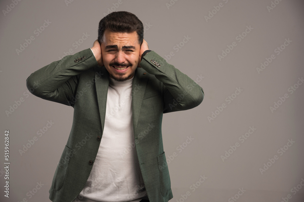 A businessman in dress code covering his ears as it gets loud A businessman in dress code covering his ears as it gets loud