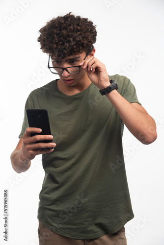 Young boy with curly hairs checking messages and gets surprized