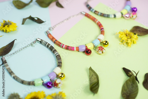 cute cat necklace on a green, blue, pink background with dried flowers untidy