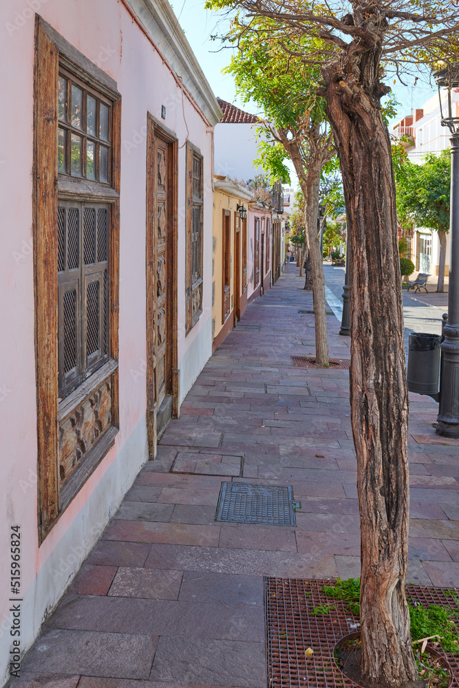 City view paved sidewalk with trees and residential houses or buildings on a quiet street in Santa Cruz, La Palma, Spain. Historical spanish and colonial architecture and famous tourism destination