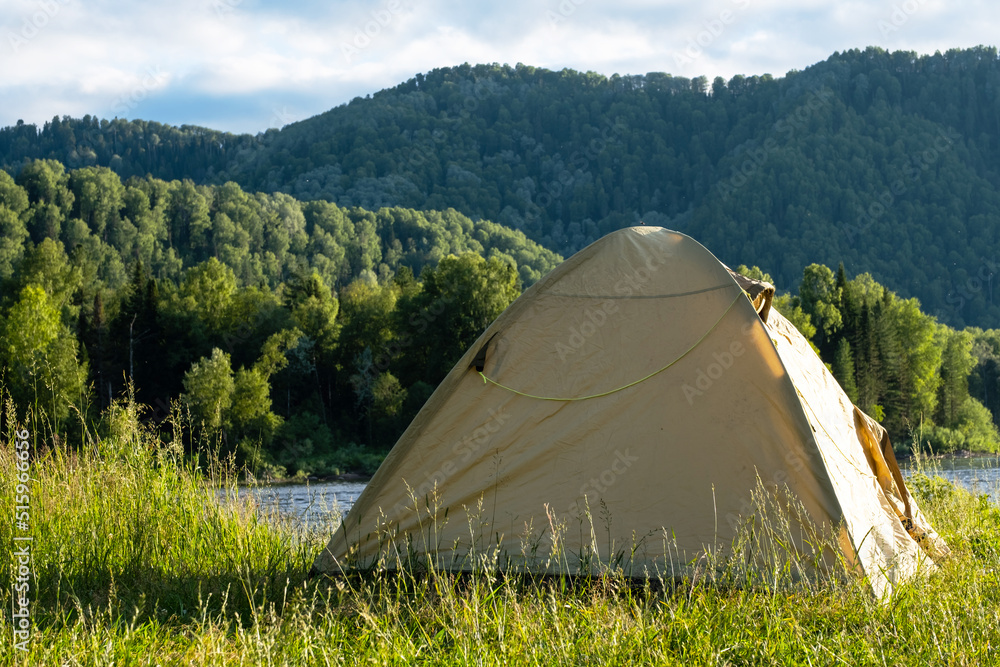 Tourist tent on river bank. Camping tent near mountain river. Local tourism, weekend at nature.