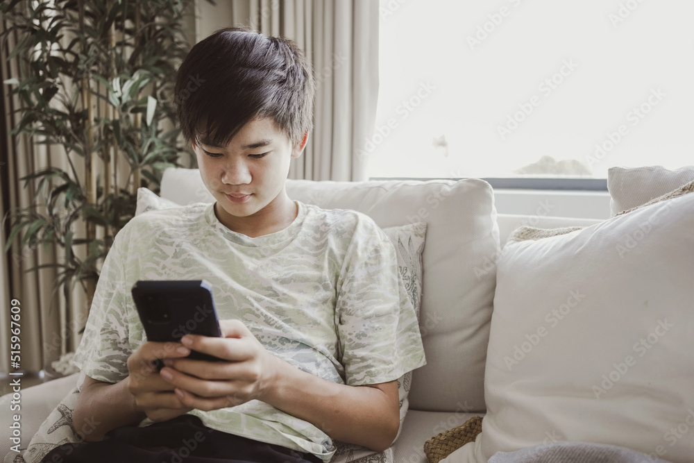 mixed Asian teen boy using smartphone at home, technology lifestyle concept mixed Asian teen boy using smartphone at home, technology lifestyle concept