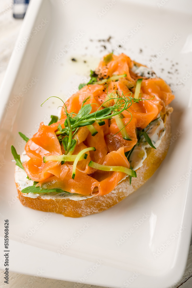 Bruschetta with salmon and cheese on white plate macro close up, vertical