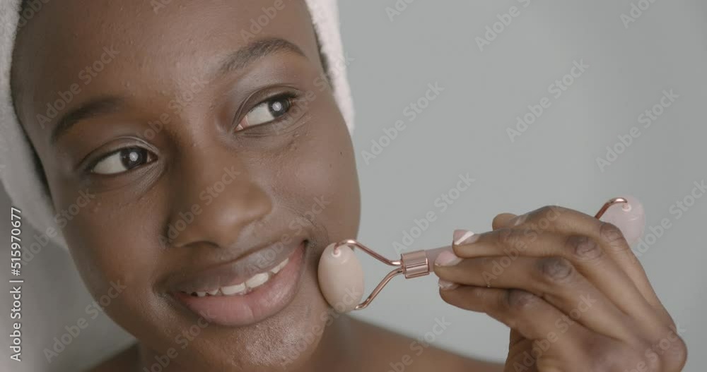 Black girl doing facial massage with a roller Black girl doing facial massage with a roller