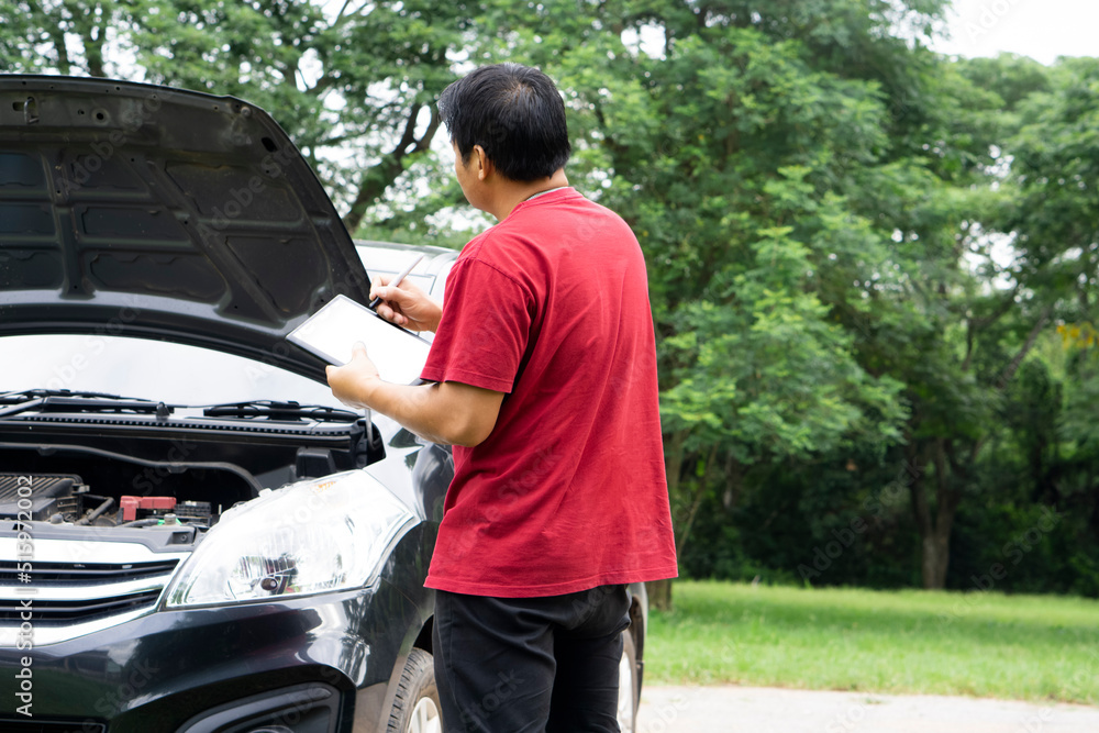 Asian man insurance agent is checking or examining car engine that broken from accident at outdoor. Concept : Accident insurance claim process. Asian man insurance agent is checking or examining car engine that broken from accident at outdoor. Concept : Accident insurance claim process.