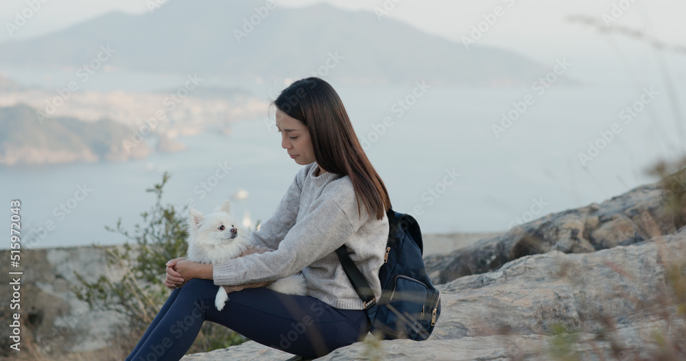 Woman go hiking with her dog and sit on the top of the mountain