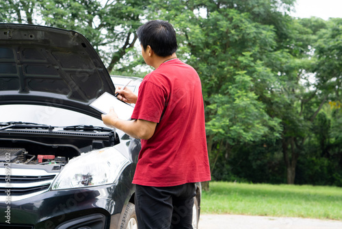 Asian man insurance agent is checking or examining car engine that broken from accident at outdoor. Concept : Accident insurance claim process.