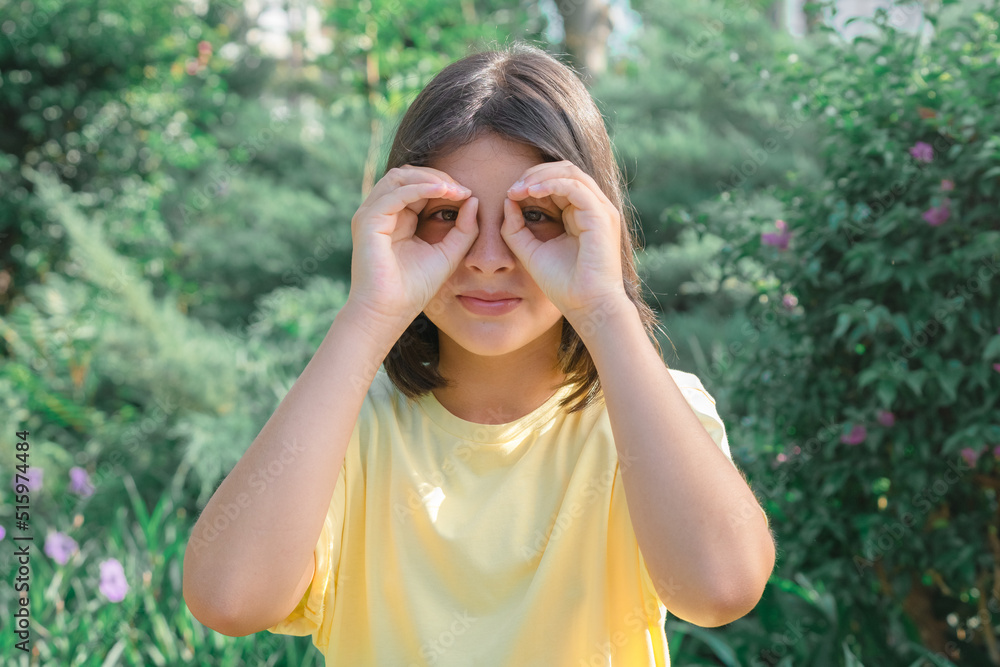 A young girl makes glasses with her hands. A young girl makes glasses with her hands.