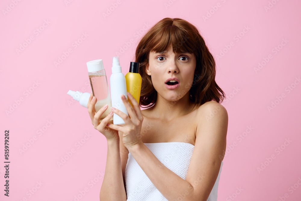 horizontal photo on a pink background of a shocked, surprised woman, holding various care products in her hands and looking at the camera with her mouth wide open horizontal photo on a pink background of a shocked, surprised woman, holding various care products in her hands and looking at the camera with her mouth wide open