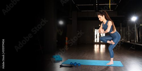 woman doing yoga in the gym, standing in yoga pose for balance, asana on one leg, healthy lifestyle and natural balance concept. banner.
