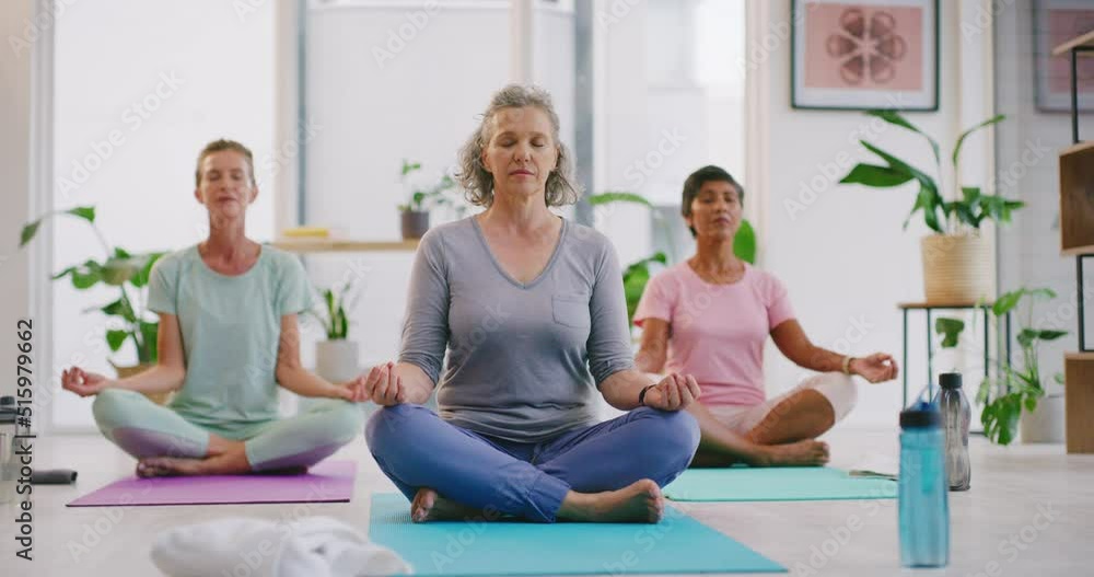 Mature women meditating in lotus pose in zen yoga class. Diverse group