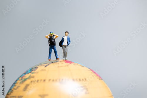 Travelers in miniature standing on the globe and making their way to their destination  Travel concept