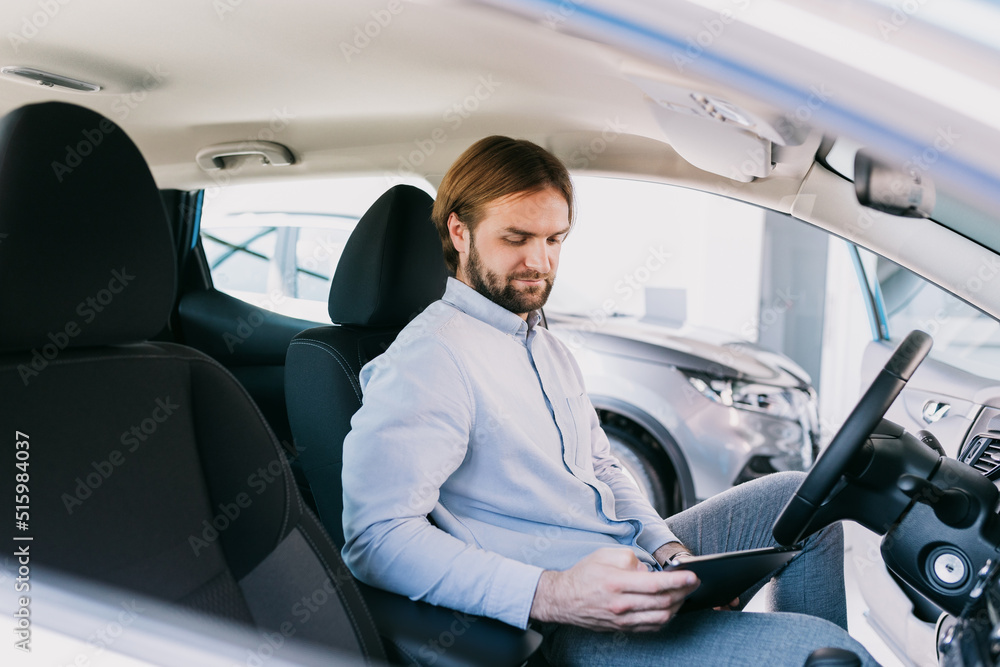 The manager of the dealership performs diagnostics of the car before sale using a tablet The manager of the dealership performs diagnostics of the car before sale using a tablet