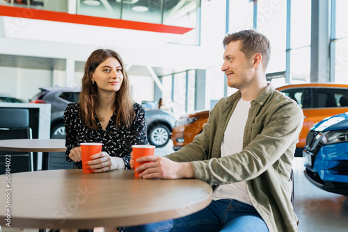 Buying a family car. The couple drinks coffee at the table while the paperwork for the car is being processed
