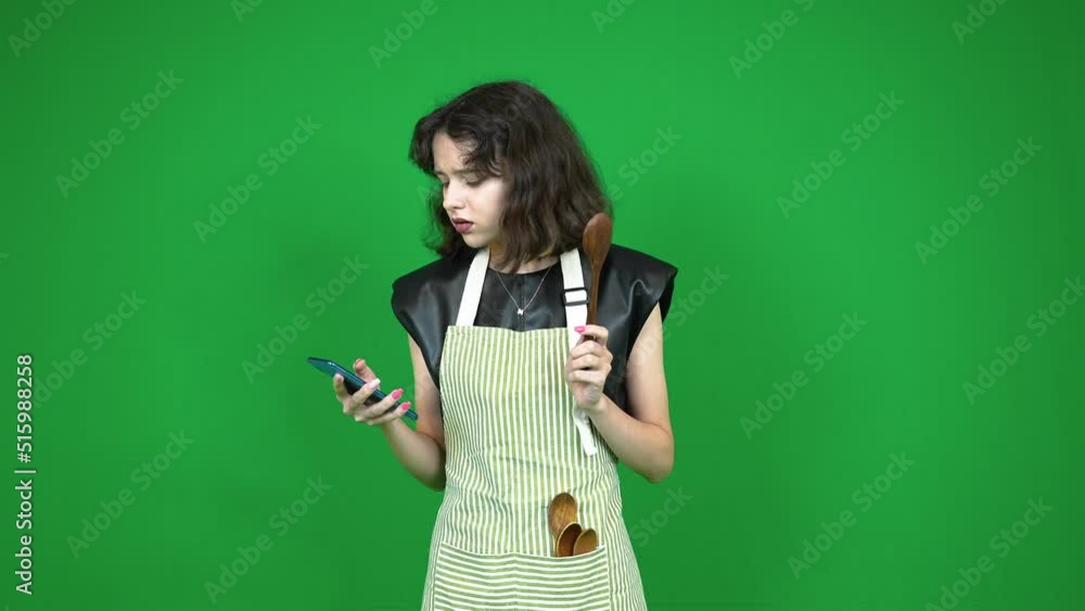 Young housewife in apron holding wooden spoons Young housewife in apron holding wooden spoons