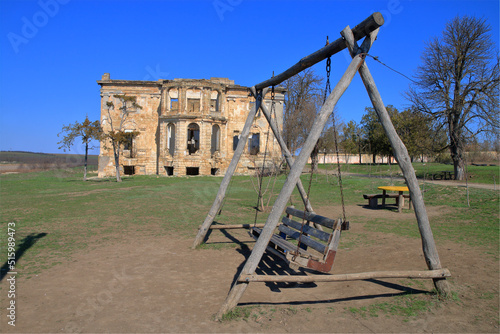 Wooden swing against the backdrop of an old abandoned estate.