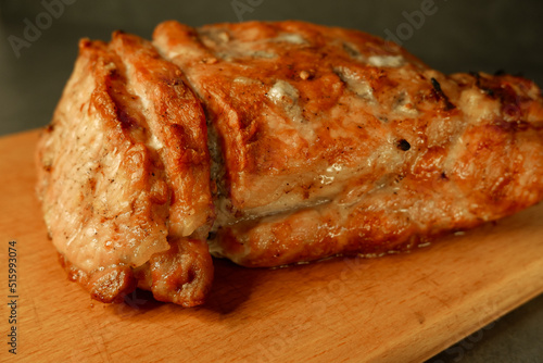 Fried pork steak in frying pan, close up view. Large fried piece of meat on a cutting wooden board