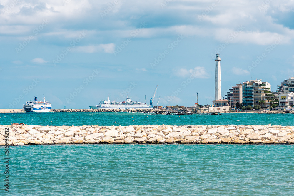 Bari port or harbor with breakwater, cruise ships or ferry boats and lighthouse on background