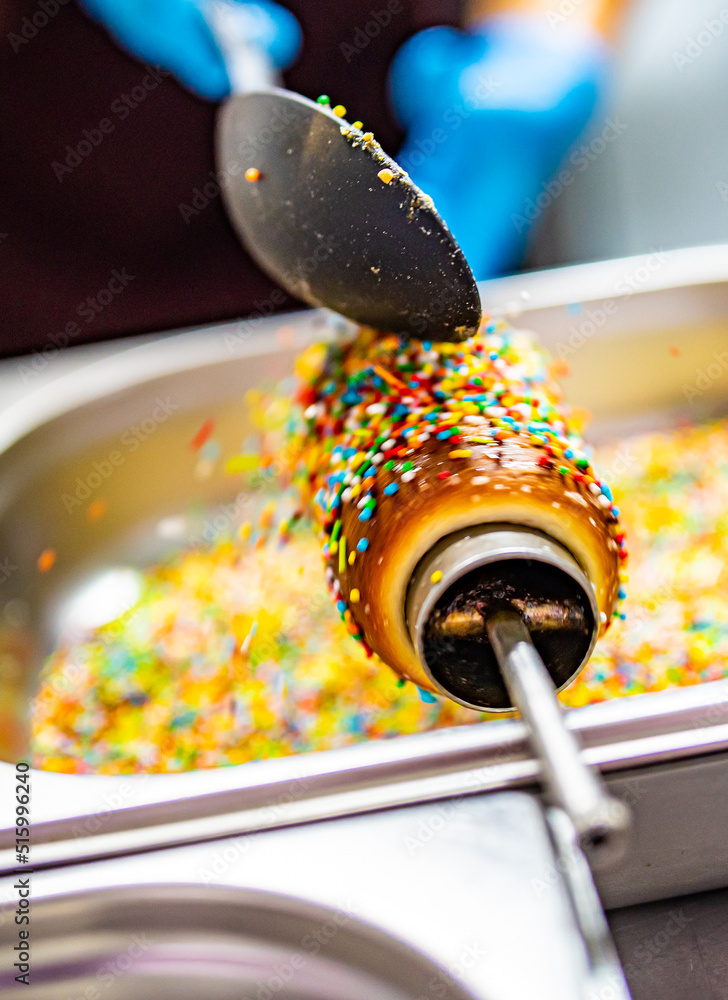 hand of chef baker making Trdlo or Trdelnik, Traditional tasty baked Czech Republic. street food hand of chef baker making Trdlo or Trdelnik, Traditional tasty baked Czech Republic. street food