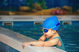 little girl in waterproof goggles and a swimsuit at a swimming class in an indoor pool, sports and healthy lifestyle for children