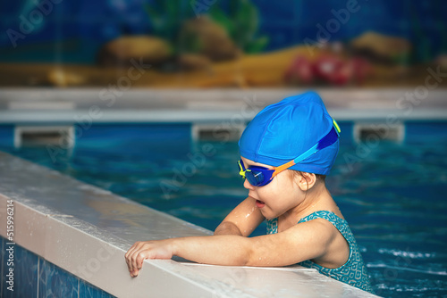 little girl in waterproof goggles and a swimsuit at a swimming class in an indoor pool, sports and healthy lifestyle for children © Ольга Рязанцева