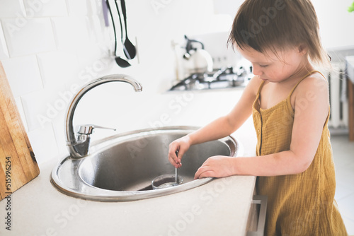 Funny baby washes his hands in bright real kitchen