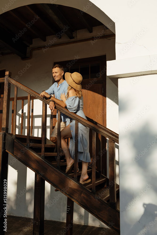 Happy lovers stand and hug on a wooden balcony in the house. Country life. Valentine's Day. Happy lovers stand and hug on a wooden balcony in the house. Country life. Valentine's Day.