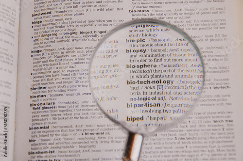 The definition of the word Biotechnology in a dictionary, under magnifying glass, translator and language concept photo