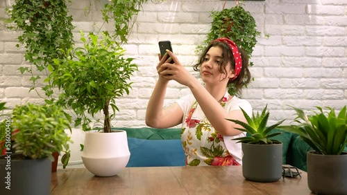 Young female gardener taking pictures of  house plant