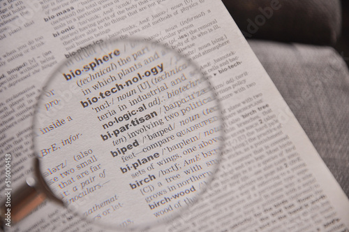 The definition of the word Bipartisan in a dictionary, under magnifying glass, translator and language concept photo