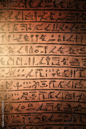 Egyptian hieroglyphs on a sandstone slab in the rays of the evening sun.
