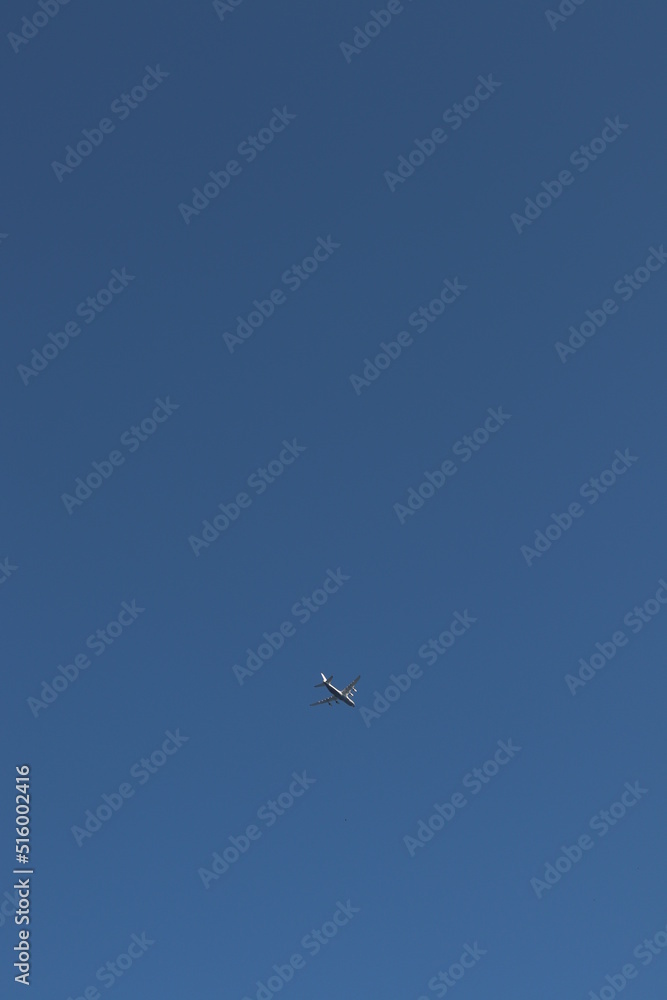 A beautiful image of a white airplane flying in a cloudless blue sky.