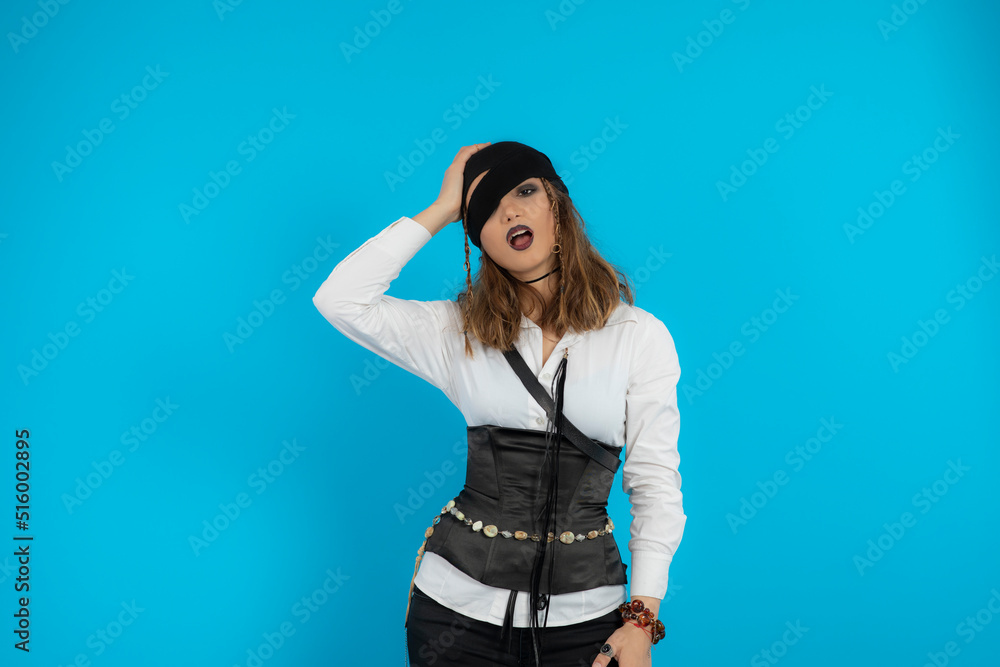 Fototapeta premium Young pretty pirate girl stand on blue background