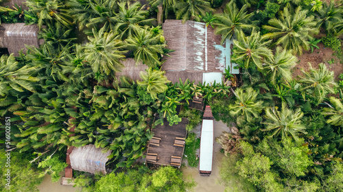aerial top down view of straw roof home with pier and boat along the Mekong river in Vietnam surrounded by tropical jungle